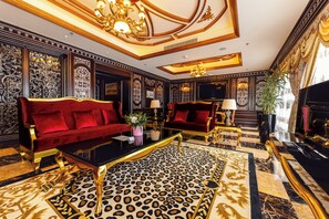 A luxurious room with a red sofa, a leopard print rug, and a grand piano. - Hotels & Preference Hualing Tbilisi (Tbilisi)