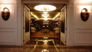 A grand hallway with a reflective floor leading to a seating area with a chandelier. - Ramada Plaza by Wyndham Chandigarh Zirakpur (Dera Bassi)