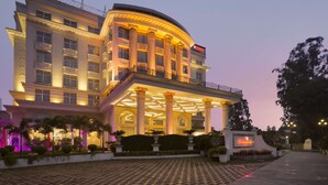 A large, multi-story hotel with a grand entrance, columns, and a well-lit facade. - Ramada Plaza by Wyndham Chandigarh Zirakpur (Dera Bassi)