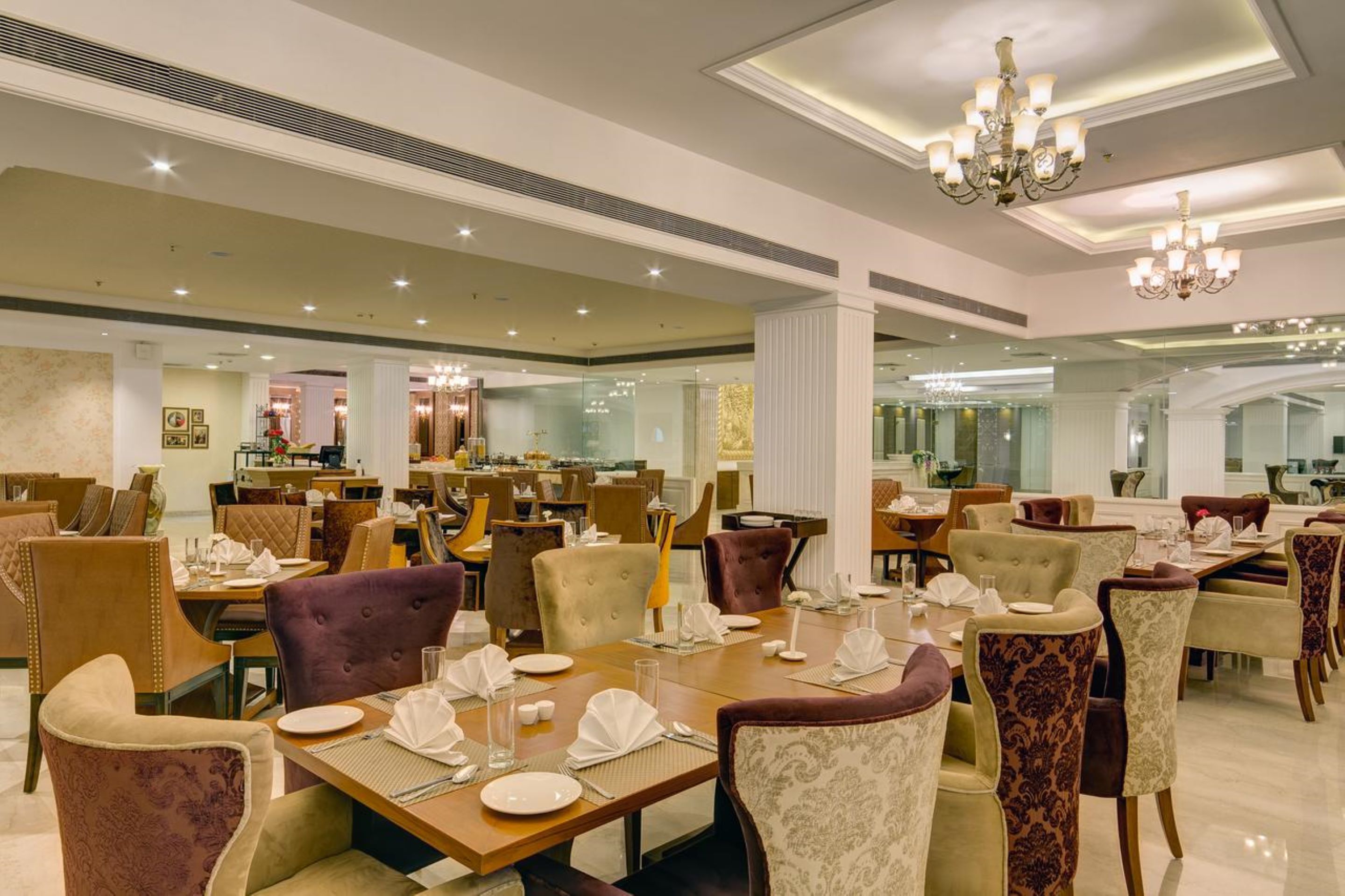 Un comedor amplio con múltiples mesas y sillas, elegantes candelabros y un diseño interior moderno.