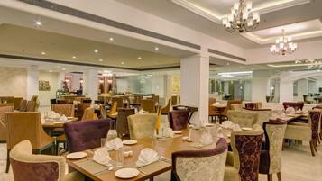 Un comedor amplio con múltiples mesas y sillas, elegantes candelabros y un diseño interior moderno.