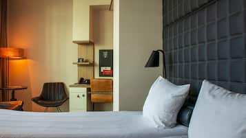 A hotel room with a large bed, two chairs, a desk, and a lamp.