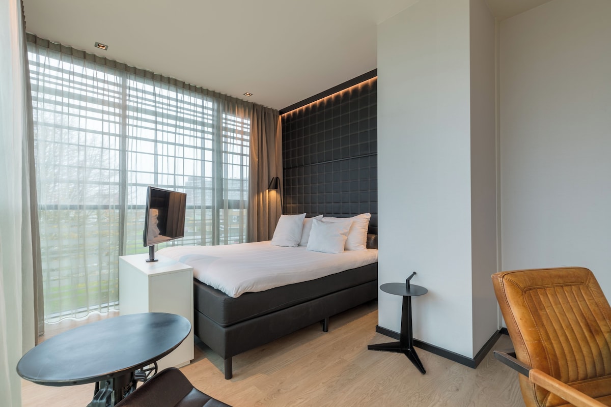 Una habitación de hotel moderna con una cama grande, un escritorio, una silla y un televisor.