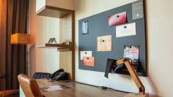 Een vergaderruimte met een houten bureau, een telefoon en een prikbord met verschillende berichten.
