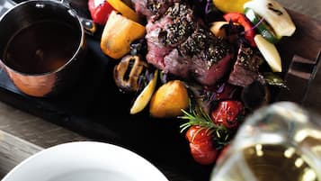Een eettafel met een bord eten, een saladekom en een glas wijn.
