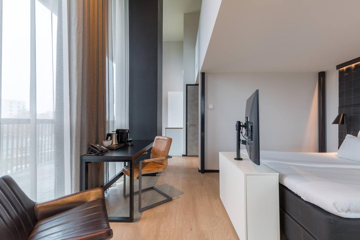 Una habitación de hotel moderna con cama, escritorio, silla y televisión.