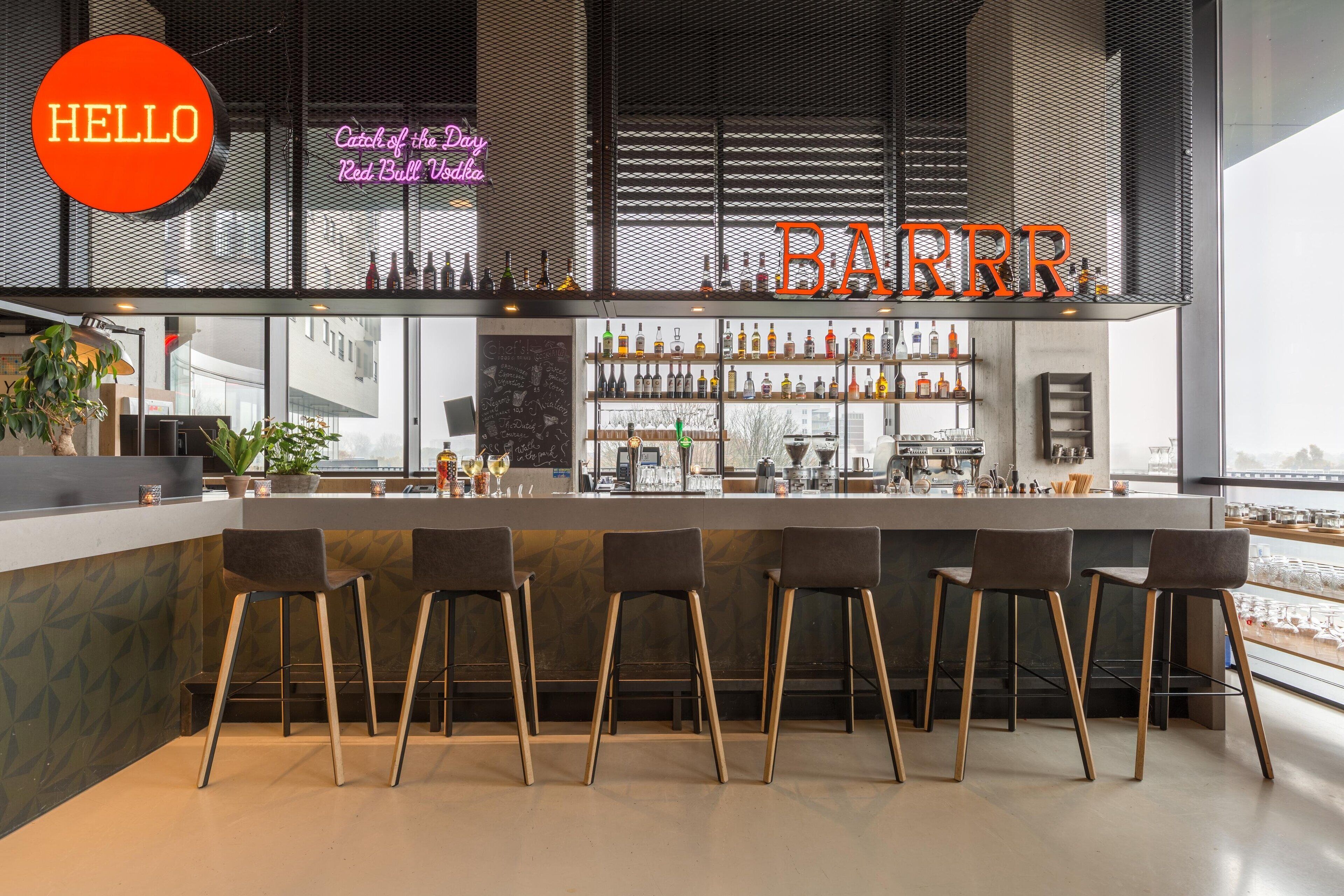 A bar area with a neon sign reading "HELLO" and "BARRR." There are bar stools and shelves with bottles.