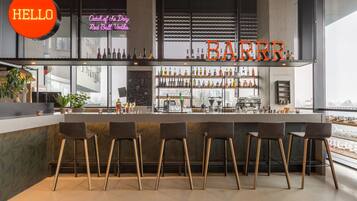 A bar area with a neon sign reading "HELLO" and "BARRR." There are bar stools and shelves with bottles.