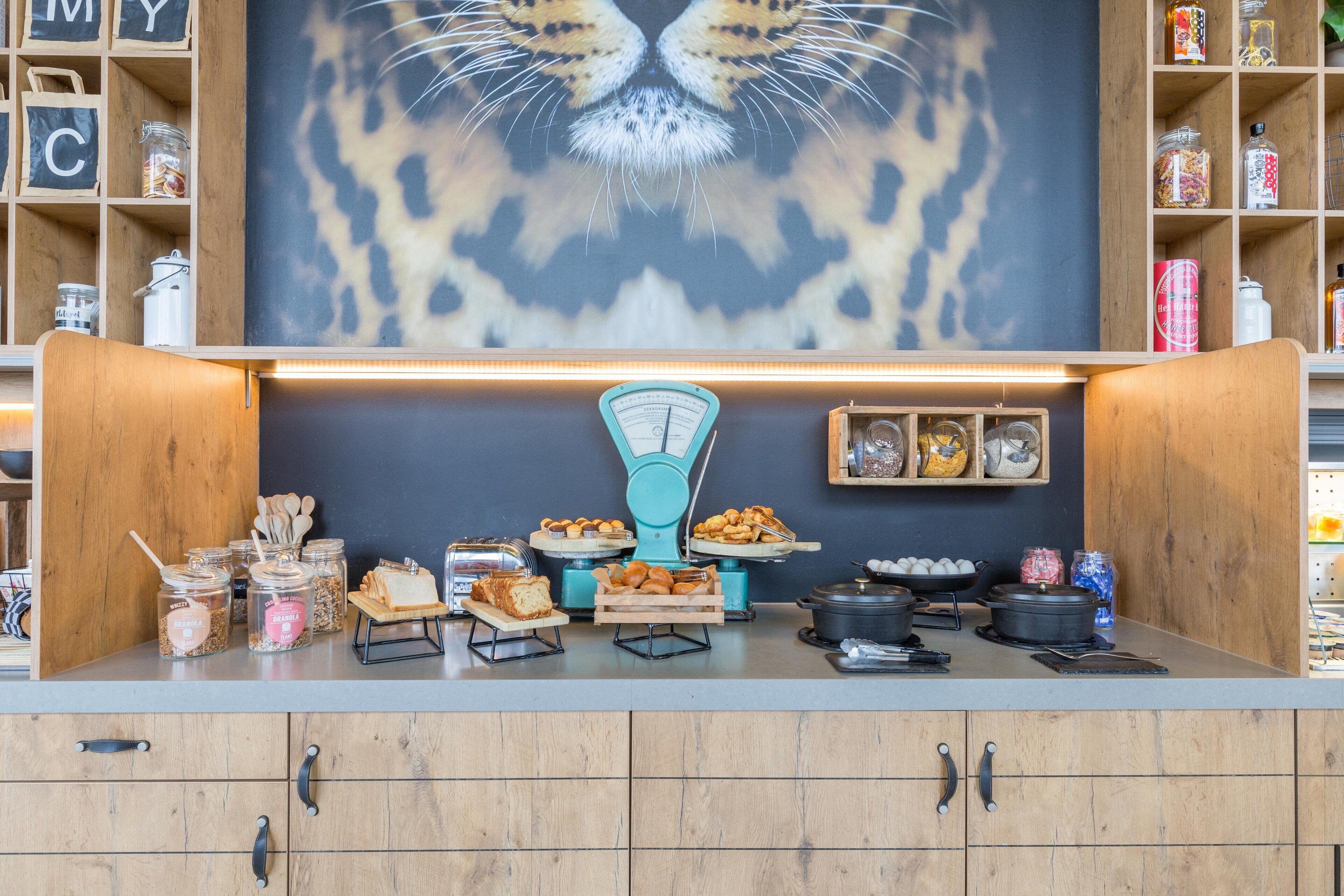 A breakfast buffet with various food items and a large cat-themed artwork on the wall.