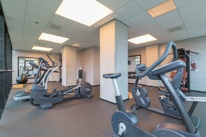 Uma academia com vários equipamentos de exercício, um espelho grande e uma parede de tijolos.