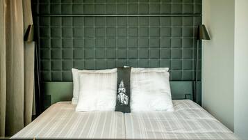 Ein ordentlich gemachtes Bett mit einer gestreiften Bettdecke und zwei Kissen, eines davon mit einer Zierkissenhülle.