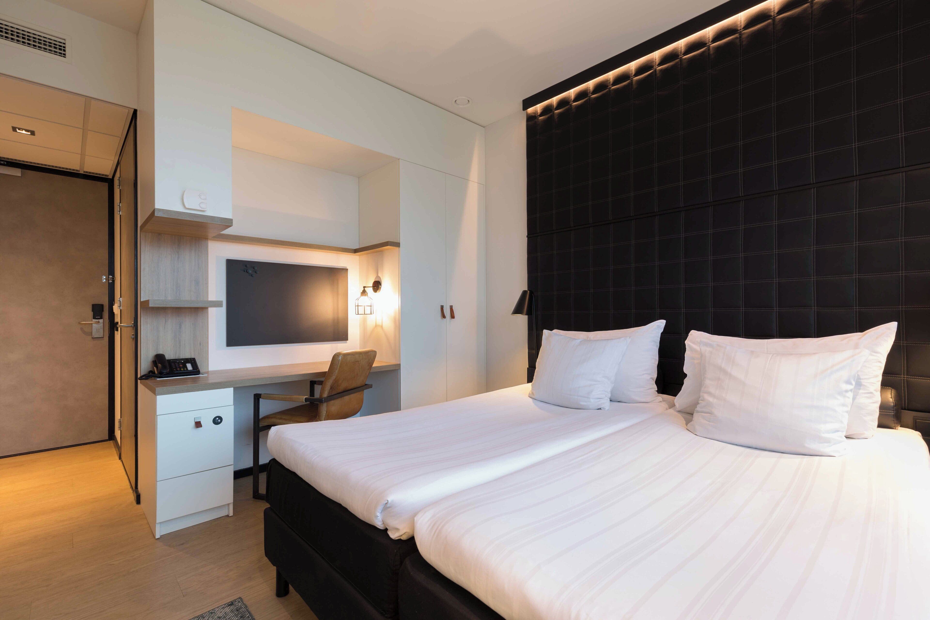 Une chambre d’hôtel moderne, dotée d’un grand lit, d’un bureau et d’une chaise.