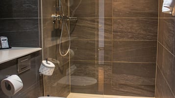 A modern bathroom with a glass-enclosed shower, a white toilet, and a towel rack.