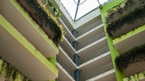 Un atrium à plusieurs niveaux, doté de balcons, de verdure et d’un escalier central en colimaçon.