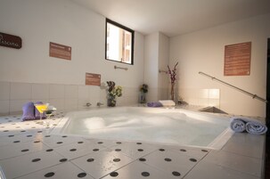 A spa room with a large bathtub, a window, and several informational signs on the walls.