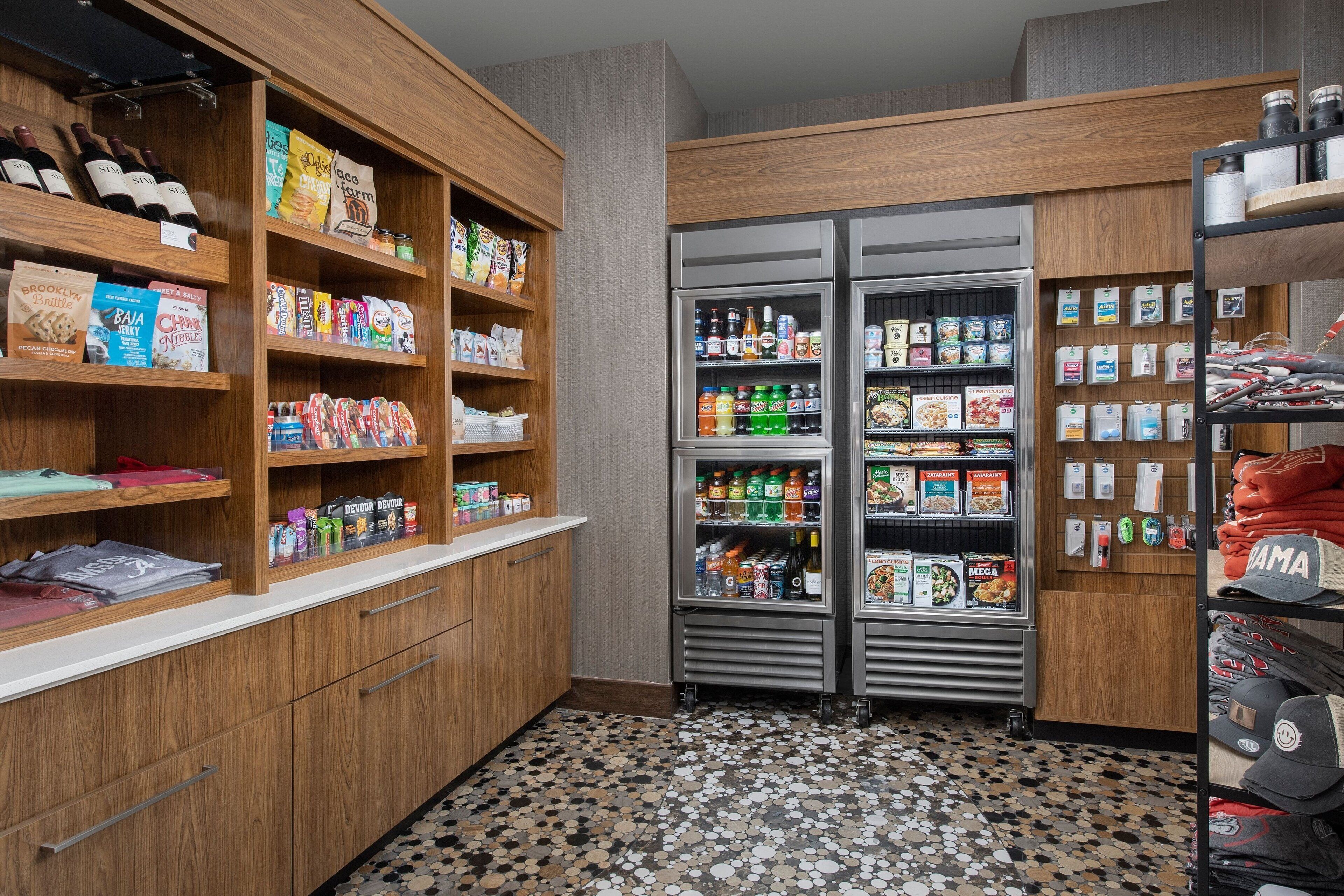 A kitchenette with wooden cabinets, a tiled floor, and various food and drink items.
