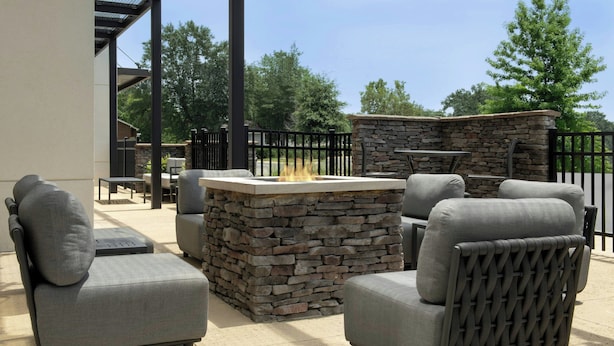 Un patio al aire libre con mobiliario de piedra y metal, incluyendo dos sofás y una mesa.