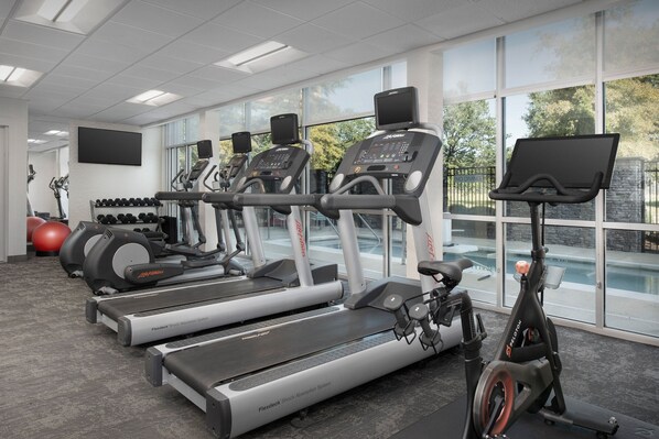Un gimnasio con cintas de correr, elípticas y una bicicleta estática.