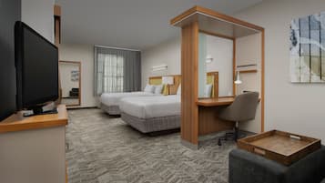 A hotel room with two beds, a desk, a TV, and a large window with curtains.