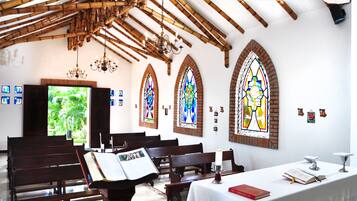 Interior de iglesia con bancos de madera, vidrieras y un altar blanco.