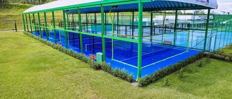 A covered swimming pool with a green frame and a blue interior, surrounded by grass.