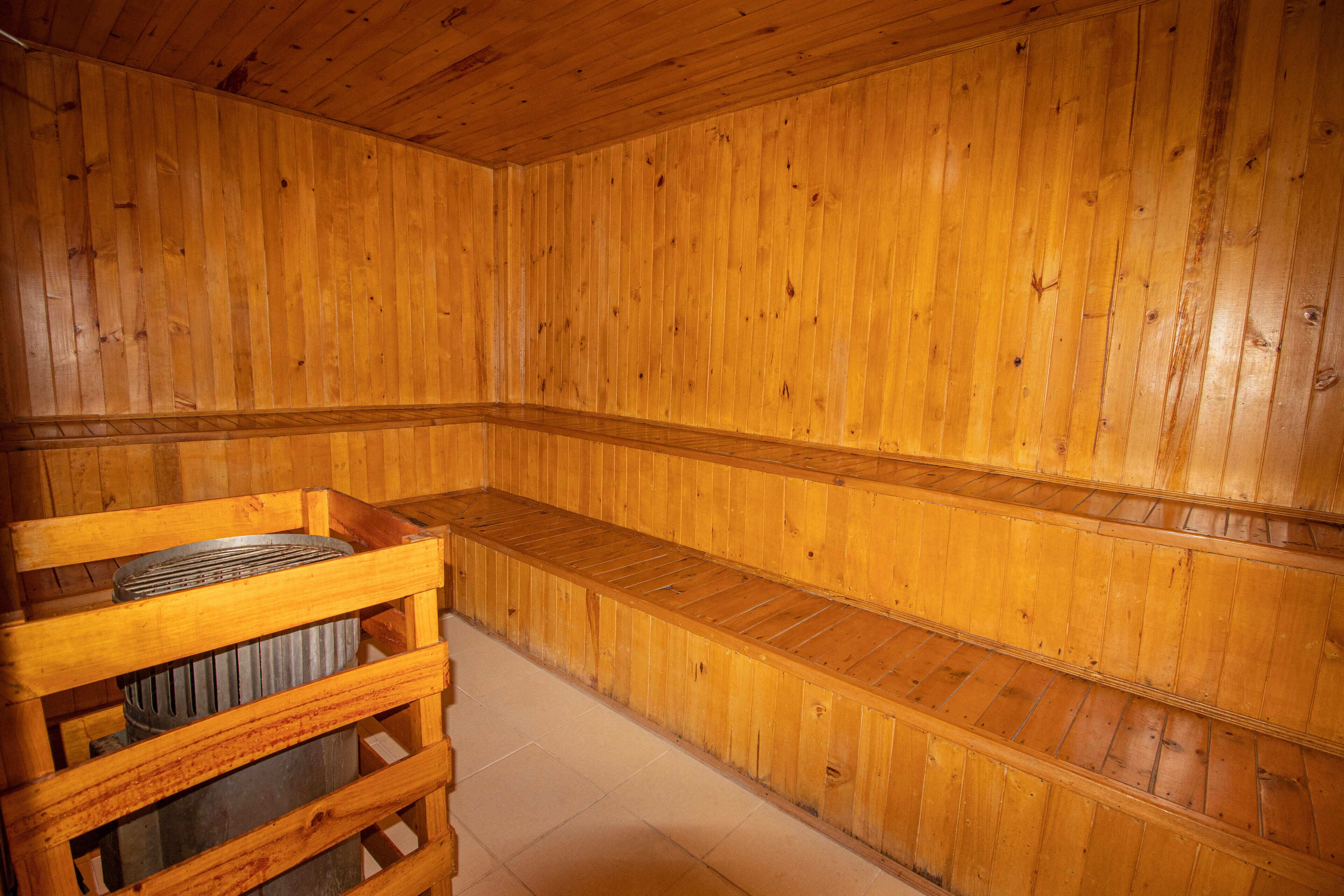 Una sauna de madera con bancos y una estructura de madera que contiene un calentador.