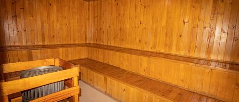 Una sauna de madera con bancos y una estructura de madera que contiene un calentador.