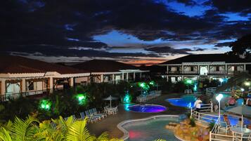 A resort pool area with multiple swimming pools, lounge chairs, and umbrellas.