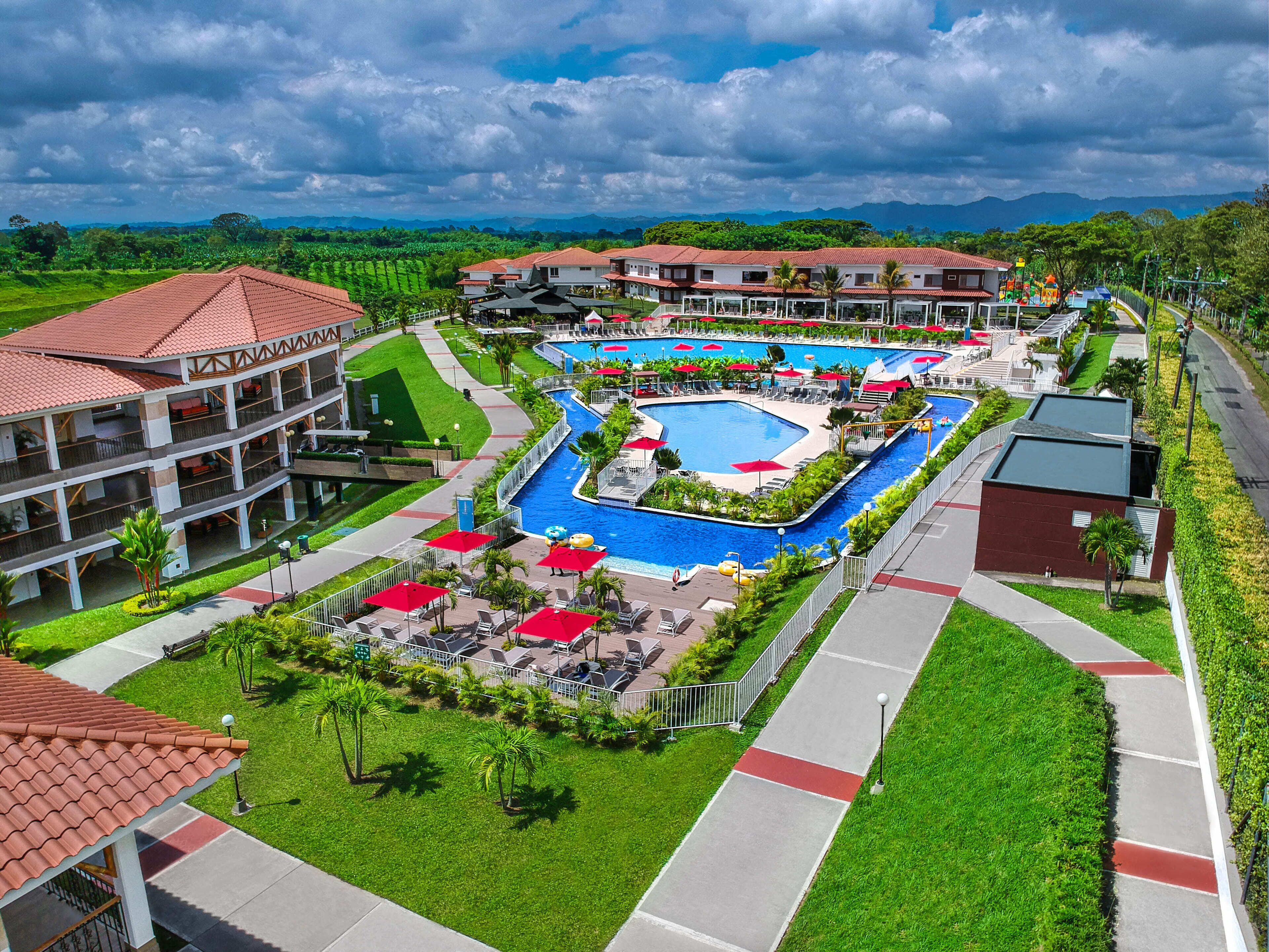 Un resort con varias piscinas, un césped bien cuidado y vistas a montañas distantes.