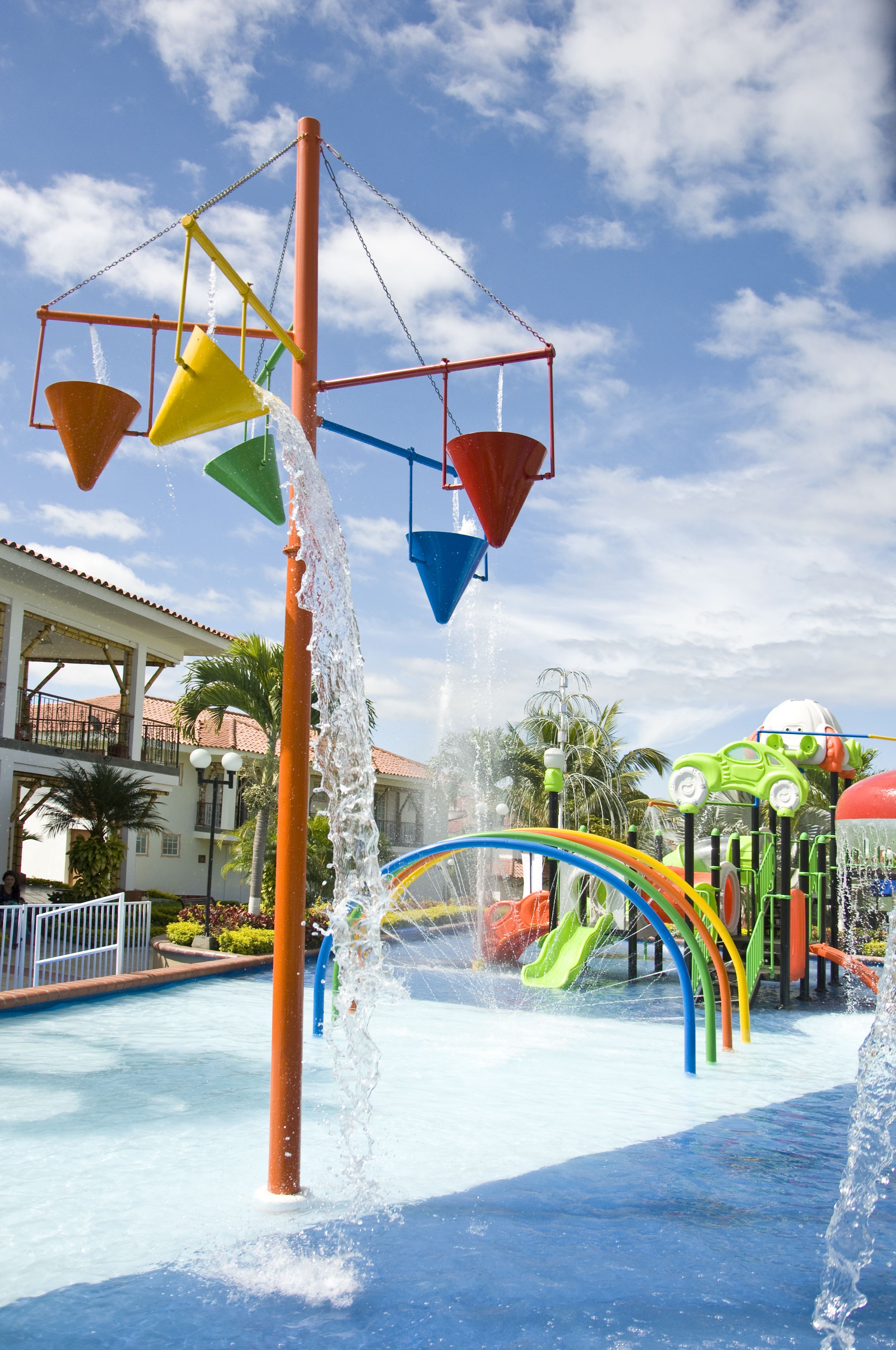 A water park with a central water feature, slides, and a building in the background.