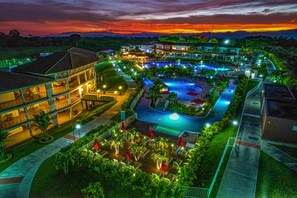 Un resort con piscina, varias edificaciones y una zona ajardinada con senderos y palmeras.