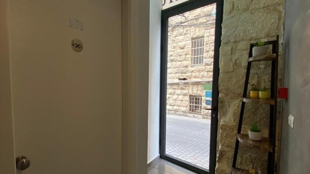 A hotel entrance with a stone wall, a door labeled "101", and a view of the street outside. - Central Boutique Hotel (Jerusalem)