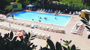 Una piscina con sillas de descanso y un pequeño pabellón.