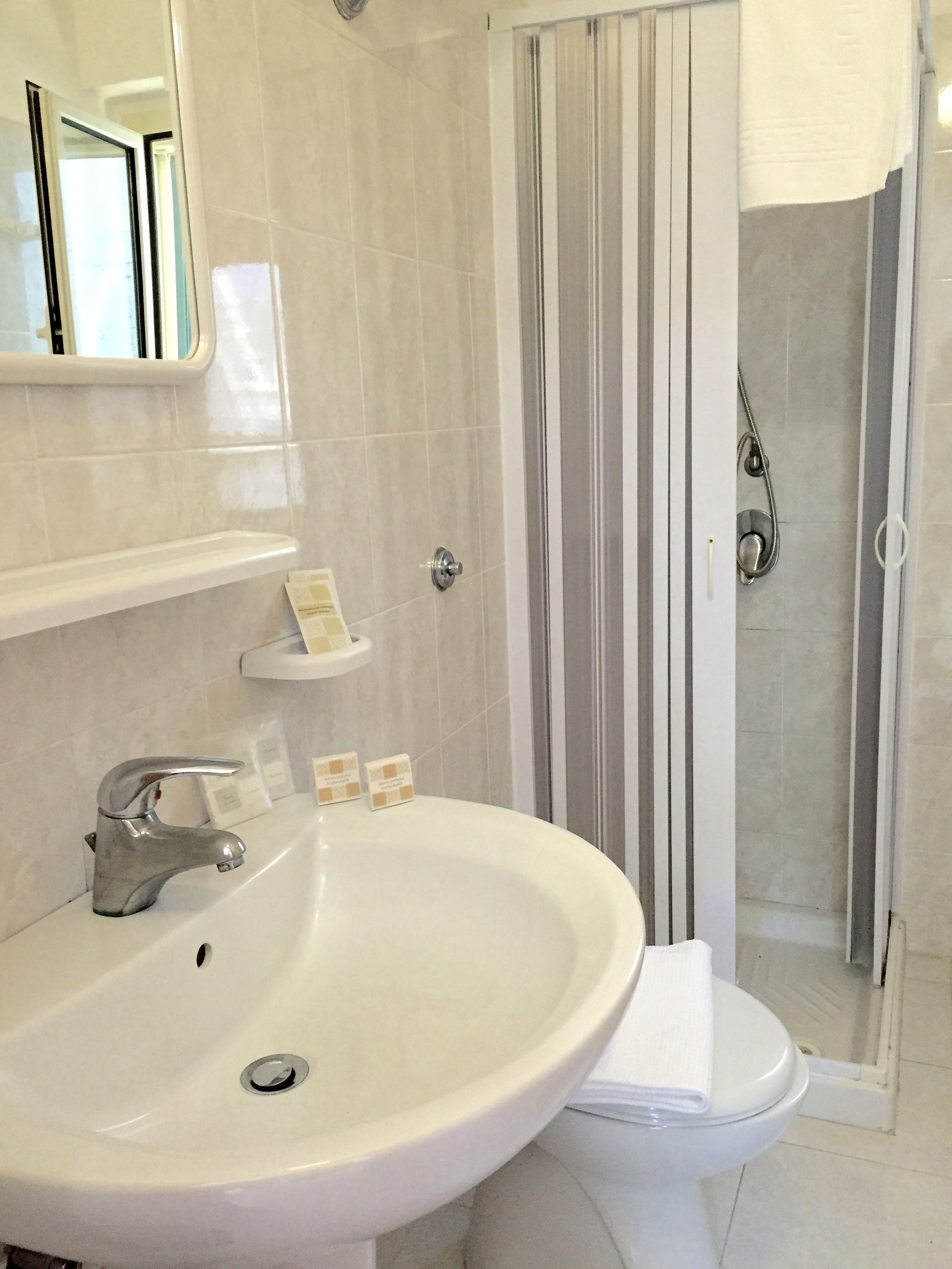 A bathroom with a white sink, a toilet, and a shower area.