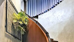 Una escalera curva con barandilla, una planta en maceta y un sillón con cojines.