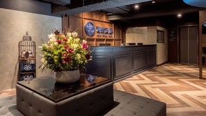 Un área de recepción de diseño moderno, con un mostrador de recepción, un arreglo floral en maceta y una jaula decorativa.