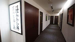 A hotel hallway with multiple doors, some marked with "EXIT" signs, and a carpeted floor.