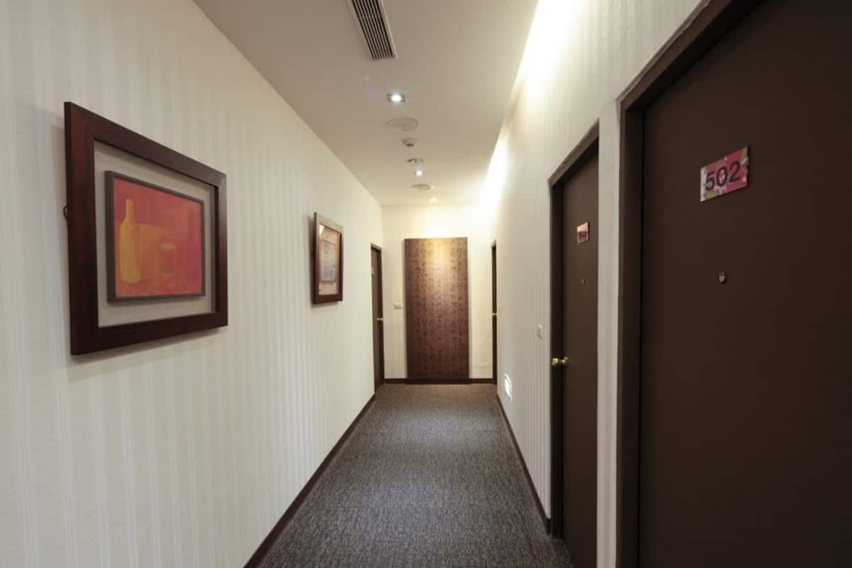 A hotel hallway with framed artwork on the walls, a carpeted floor, and a door marked with the number 502.