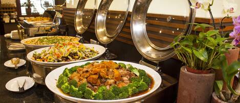 A buffet with various dishes, including a large bowl of soup with vegetables and a plate of stir-fried vegetables.