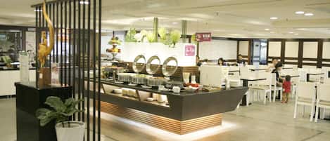 Un espace buffet avec un comptoir central, entouré de tables et de chaises.