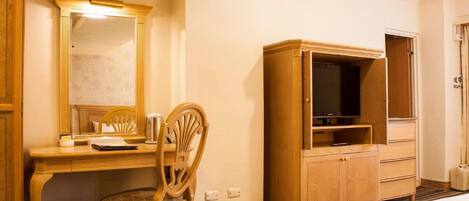 Una habitación de hotel con un escritorio de madera, una silla, un televisor sobre un mueble de madera y una cama.