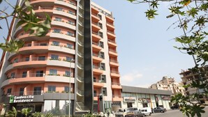 A multi-story residential building with balconies, a sign for 'Garden City Residence', and a nearby commercial building. - Garden City Residence (Dekwaneh)