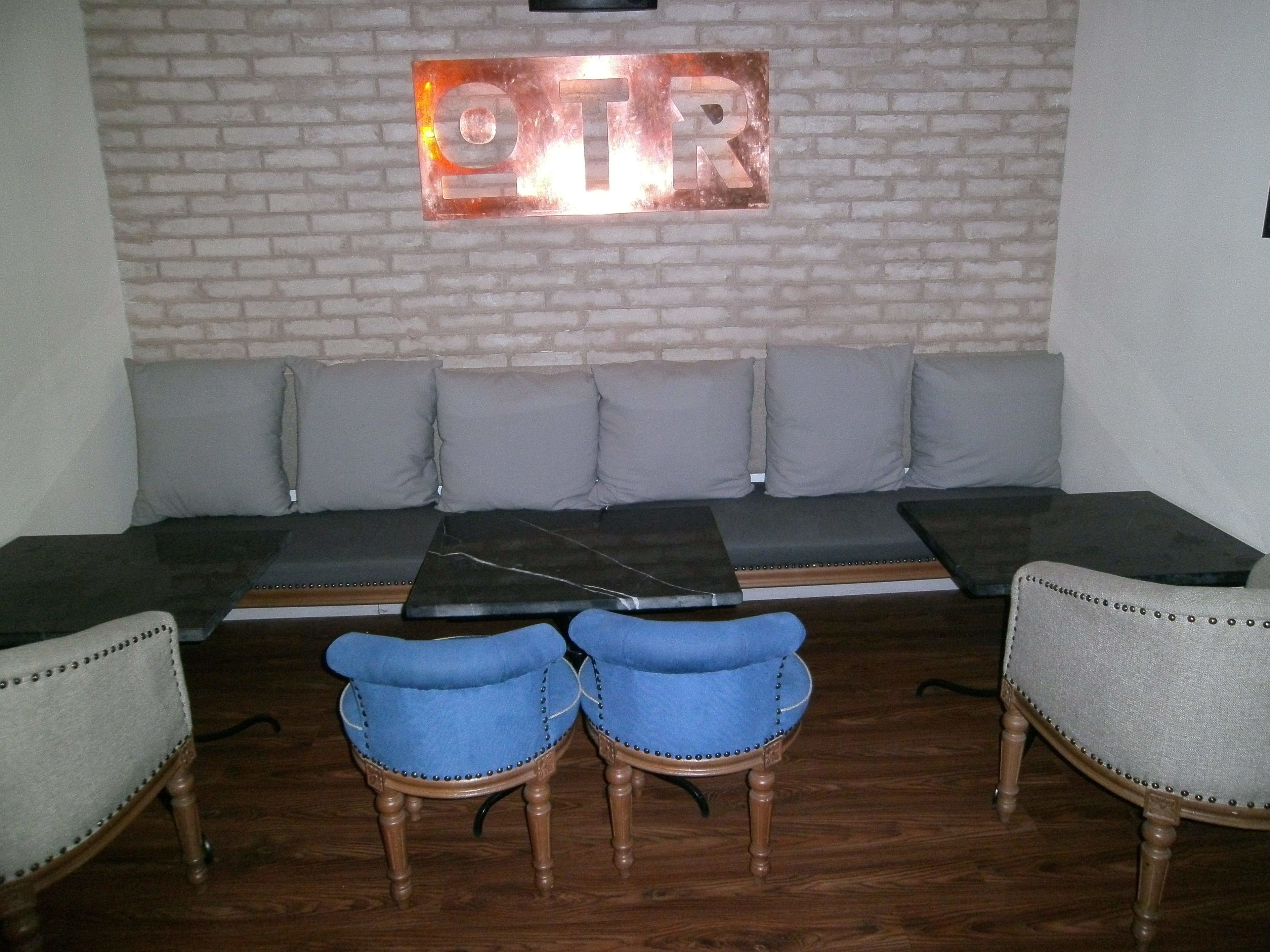 Ein Zimmer mit einer Sofagarnitur, zwei blauen Stühlen, einem Couchtisch und einer Ziegelwand mit einem Schild darüber.