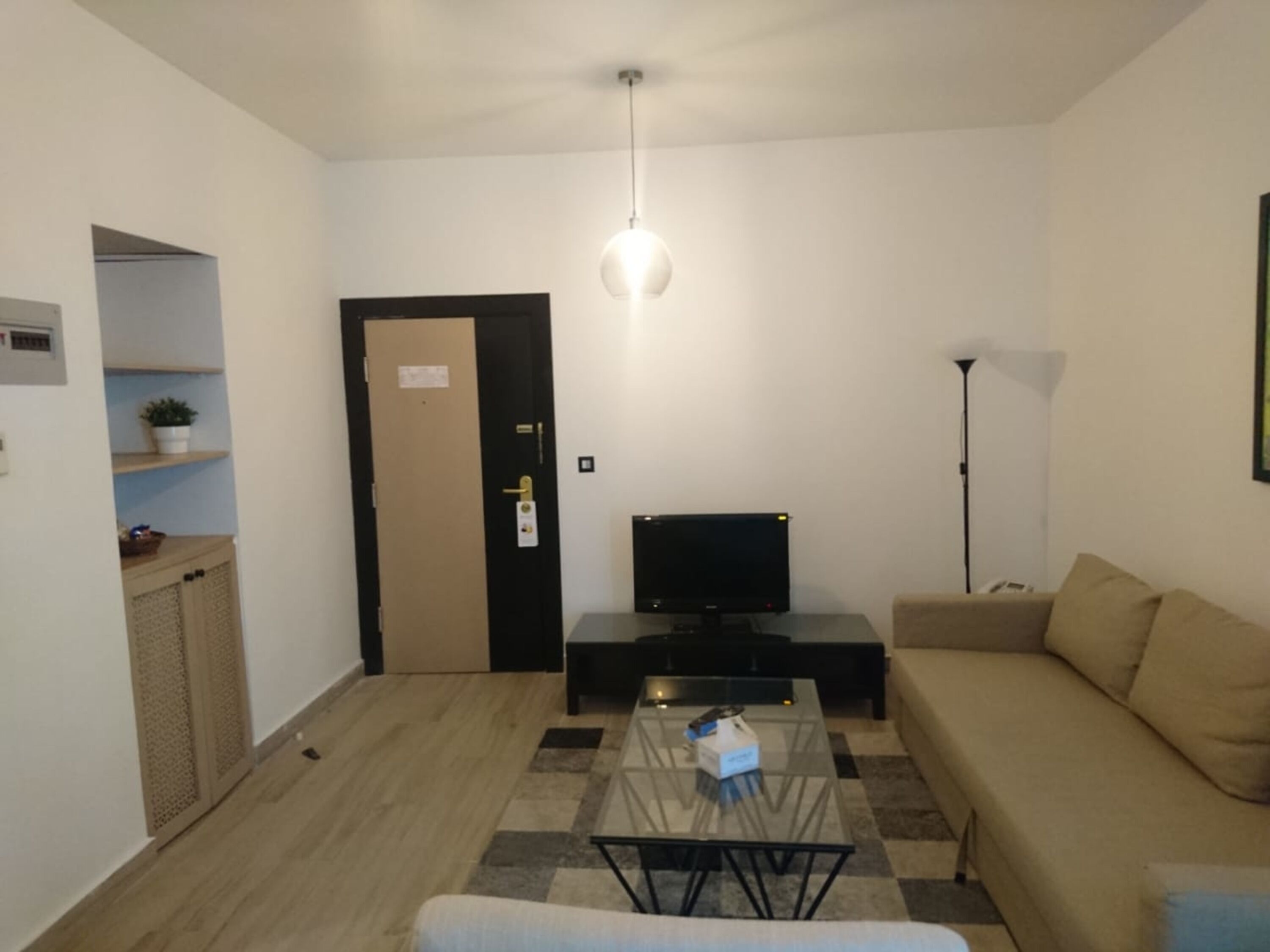 A living room with a sofa, a coffee table, a TV, and a lamp.