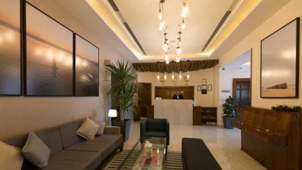A modern lobby with a reception desk, sofas, a coffee table, and artwork on the walls.