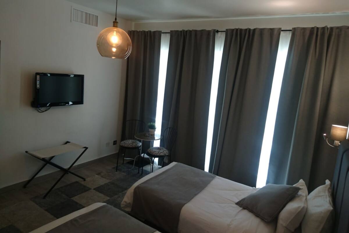 Ein Hotelzimmer mit Bett, Fernseher, Schreibtisch und Stuhl.