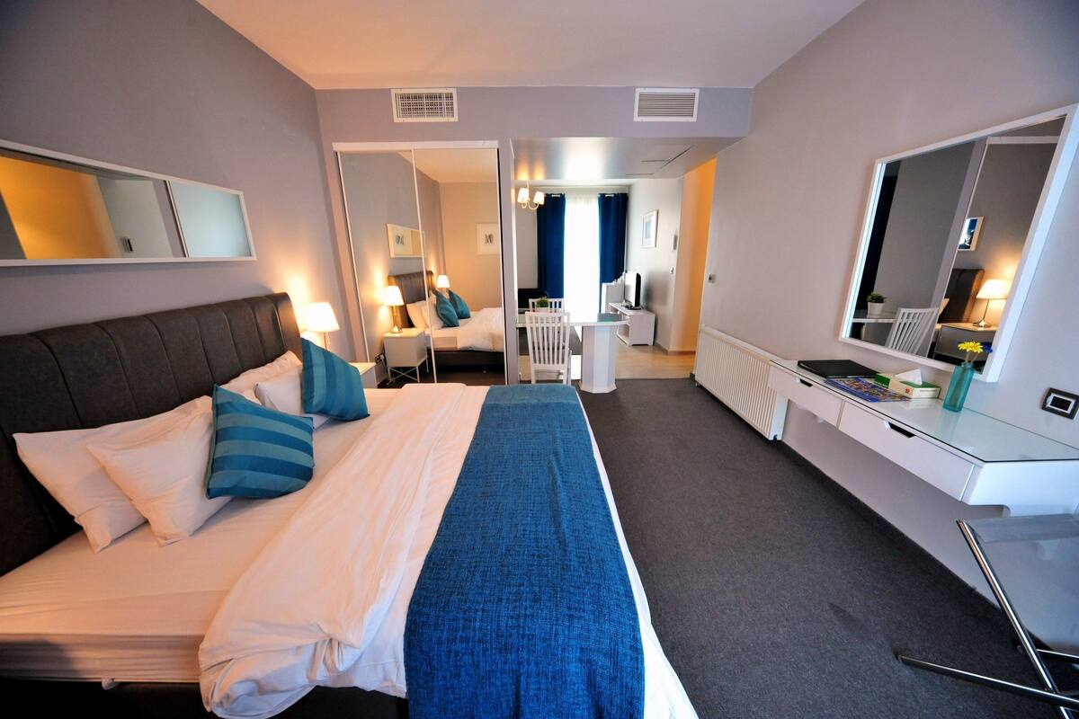Ein Hotelzimmer mit Bett, Nachttisch, Lampe und Schreibtisch mit Stuhl.