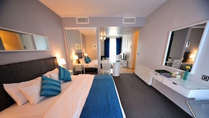 A hotel room with a bed, bedside table, lamp, and a desk with a chair.