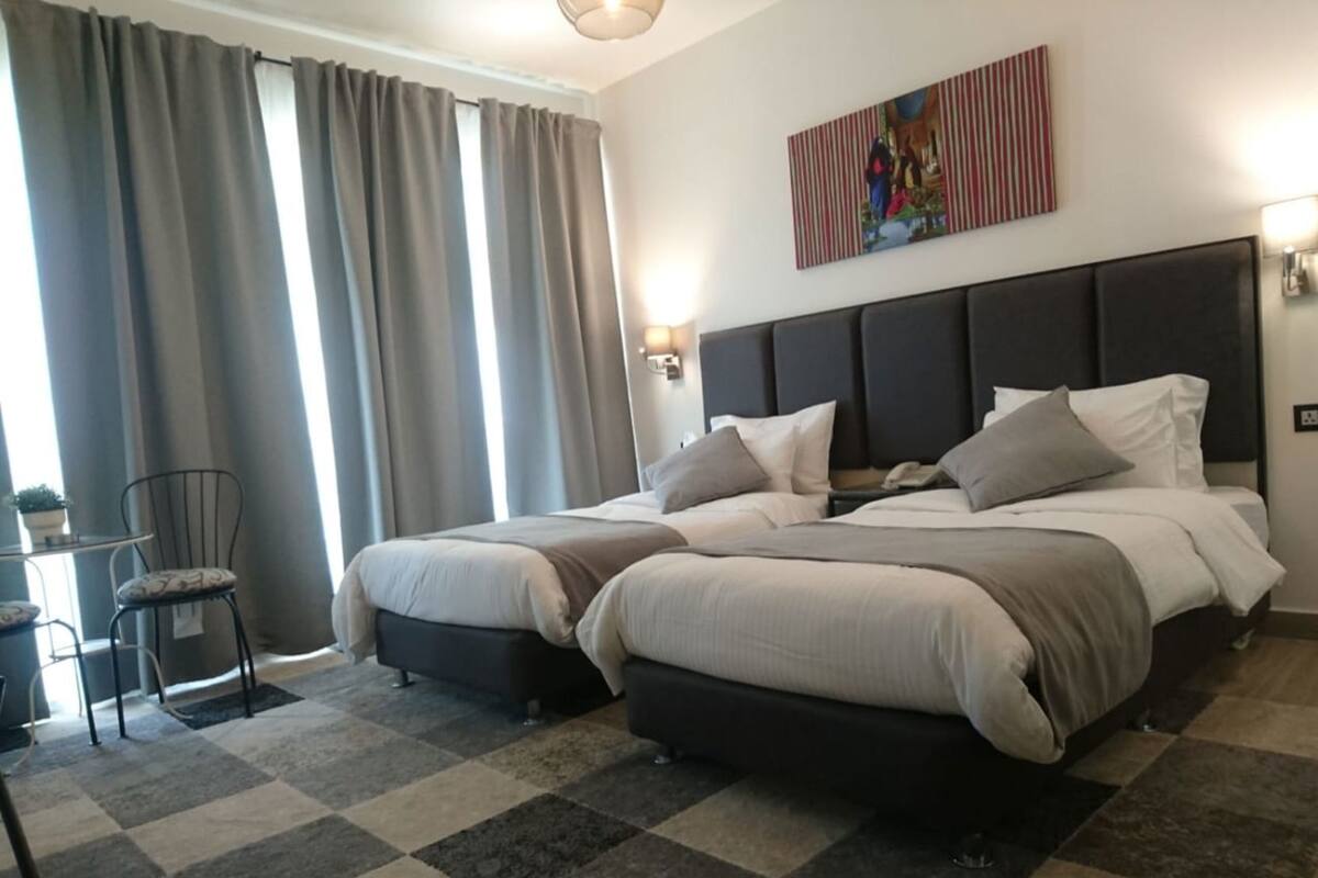 Ein Hotelzimmer mit einem großen Bett, einem Sessel, einem kleinen Tisch und einem Bild an der Wand.