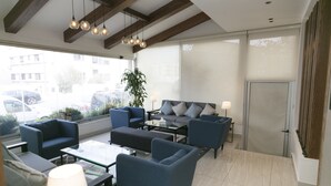 A modern lounge area with blue sofas, a glass coffee table, and pendant lighting.